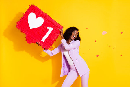 Photo of young happy smiling excited funky afro girl hold huge red pinata with flying hearts...