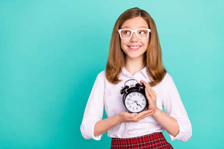 Portrait of attractive cheerful girl holding clock looking aside copy space isolated over bright teal turquoise color backgroundの写真素材