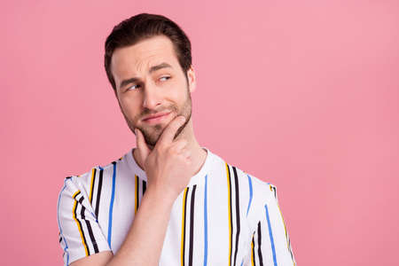 Photo of unsure brunet millennial man look empty space wear white t-shirt isolated on pink color backgroundの写真素材