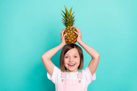 Photo of cute pretty schoolgirl dressed pink overall holding head big fruit smiling isolated...