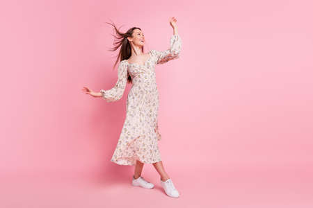 Full length body size photo pretty girl walking in windy weather looking copyspace isolated pastel pink color backgroundの写真素材