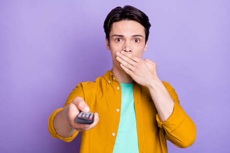Photo of young man happy positive smile cover lips hand watch tv scared terrified horror isolated...