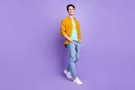 Full length photo of cute brunet millennial guy stand wear shirt jeans isolated on violet color backgroundの写真素材