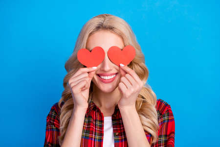 Photo of adorable charming young lady wear plaid shirt two red hearts close eyes smiling isolated blue color backgroundの写真素材