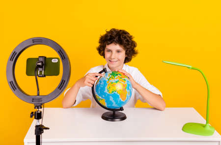 Photo of cute little brunet boy do blog wear white shirt isolated on yellow background.の写真素材