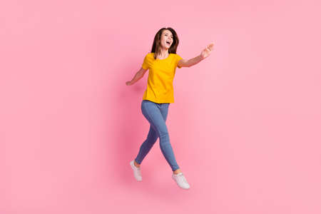 Full size photo of funky brunette hair young lady jump wear yellow t-shirt jeans isolated on pink...