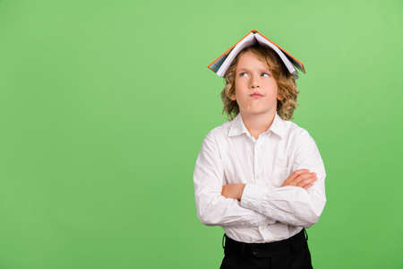 Photo of small mad blond boy crossed arms book on head wear white shirt isolated on green color backgroundの写真素材