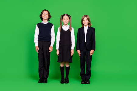 Full length body size view of attractive cheery kids classmates new grade isolated over bright green color backgroundの写真素材