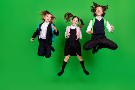 Full size photo of cool small girl boys jump wear school uniform shoes isolated on green background