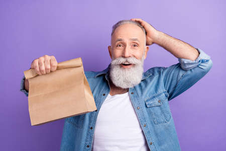 Photo of funny excited age gentleman wear jeans shirt smiling arm head holding package isolated...