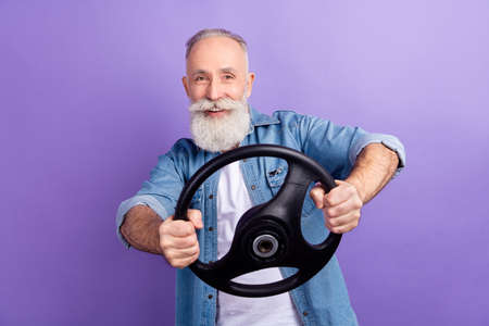 Photo of aged man happy positive smile steering-wheel ride car taxi isolated over purple color...