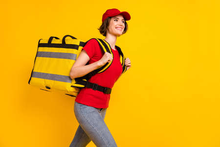 Photo portrait of woman with rucksack going forward looking copyspace delivery service isolated bright yellow color backgroundの写真素材