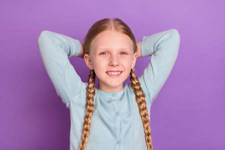 Photo of relaxed joyful small girl hands head enjoy rest white smile wear blue shirt isolated violet...