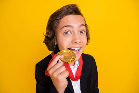 Photo of funny crazy boy teeth bite winner medal wear black uniform isolated yellow color background