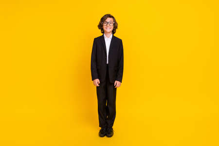 Photo of cheerful positive boy beaming smile wear eyewear black uniform isolated yellow color...