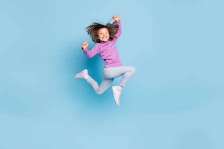 Full length body size photo small girl jumping up gesturing like winner isolated pastel blue color...