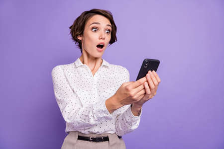 Portrait of nice brunette short hair impressed lady hold telephone wear white shirt isolated on...