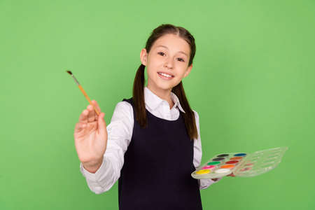 Photo portrait schoolgirl creating image with palette with paint brush on art lesson isolated pastel...
