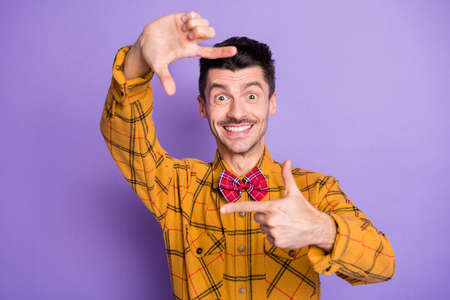 Photo of young excited man happy positives mile make frame fingers photographer isolated over purple...