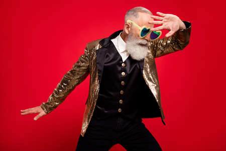 Photo of aged handsome man performance wear eyeglasses circus comic performance isolated over red color backgroundの写真素材