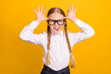 Photo of positive carefree people arms palms show horns head tongue out isolated on yellow color backgroundの写真素材