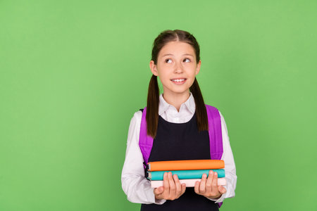 Photo portrait schoolgirl with backpack showing looking empty space dreamy with book pile isolated...