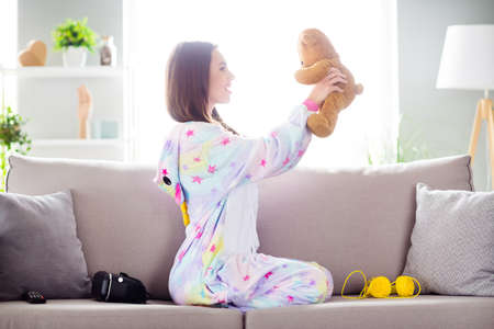 Photo of dream cheerful nice adorable serene lady play small fluffy toy bear sit sofa wear kigurumi indoorsの写真素材