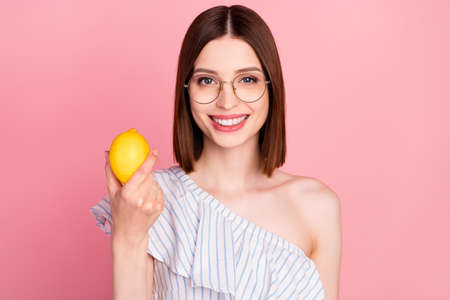 Photo of young attractive woman happy positive smile hold lemon fresh food citrus eco isolated over pink color backgroundの写真素材