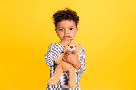 Photo portrait small boy cute hugging soft teddy bear thoughtful isolated vibrant yellow color backgroundの写真素材