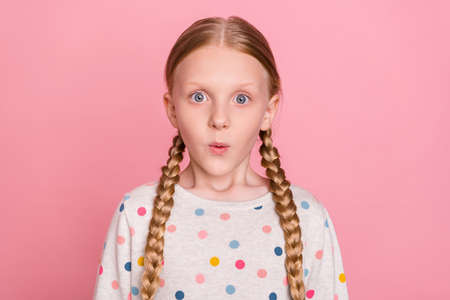 Photo of adorable impressed schoolgirl dressed dotted sweater big eyes isolated pink color backgroundの写真素材