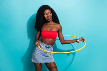 Photo of sporty pretty dark skin woman dressed top smiling holding  hoop looking empty space isolated blue color backgroundの写真素材