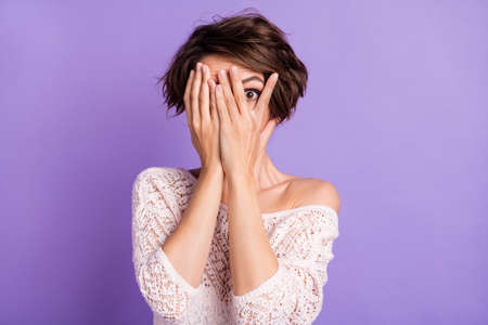Photo of charming impressed young lady dressed white shirt arms cover face isolated purple color...
