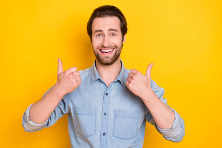 Photo portrait of young guy laughing showing thumb up like sign isolated on vibrant yellow color...