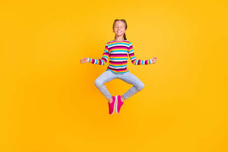 Photo of peaceful girl jump meditate close eyes wear striped shirt jeans shoes isolated yellow color backgroundの写真素材