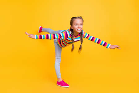 Photo of little lady hands wings fly plane wear striped shirt jeans sneakers isolated yellow color...