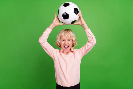 Photo of young crazy happy positive by hold hands football above head isolated on green color...