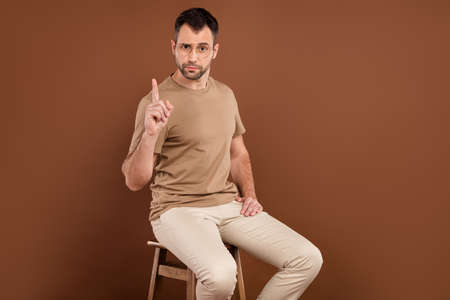Photo portrait brunet man in pastel t-shirt glasses keeping finger up giving advice isolated brown...