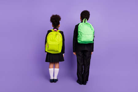 Rear back view photo of two african people kids go school wear backpack uniform isolated violet...