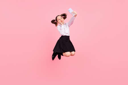 Full size photo of brown tails haired little girl jump wear uniform make selfie send air kiss...