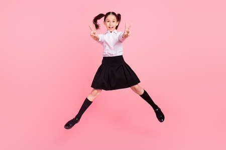 Full length photo of young happy small girl jump up show v-signs smile school isolated on pink color...