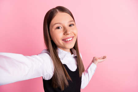 Photo of cheerful brunette little girl wear uniform formalwear hand empty space selfie isolated on...