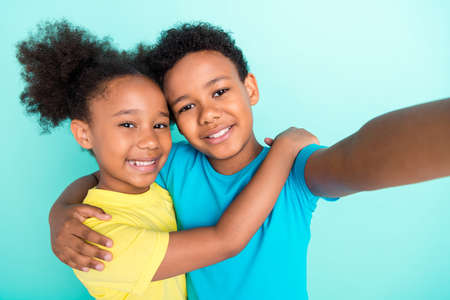 Self-portrait of nice kind cheerful friends friendship hugging best buddy isolated over bright teal turquoise color backgroundの写真素材