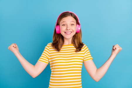 Portrait of lucky cheerful schoolchild raise fists success achieve isolated on blue color backgroundの写真素材
