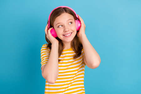 Portrait of adorable cute schoolchild touch headphones look empty space isolated on blue color...