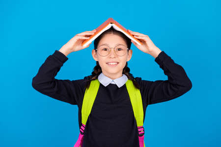 Photo of happy smiling good mood schoolgirl hold book head secure safe roof isolated on blue color...