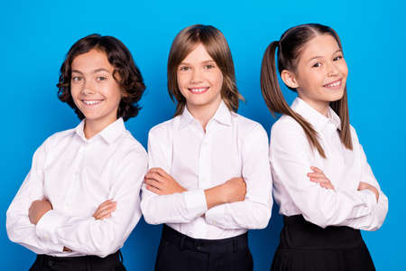 Photo of pretty charming schoolkids formalwear arms folded smiling isolated blue color backgroundの写真素材