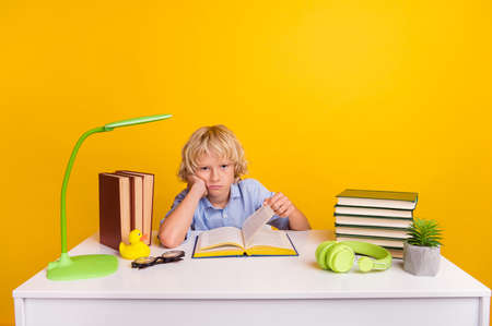 Photo of sad little boy study wear blue shirt isolated on yellow color background