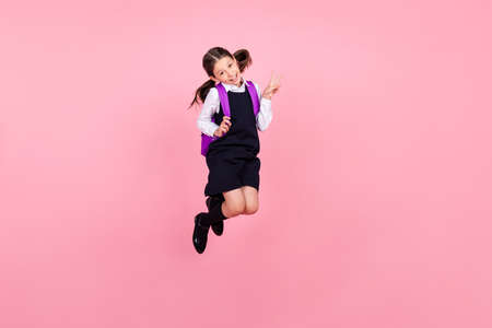 Full length body size photo schoolgirl jumping up with recksack showing v-sign gesture isolated...