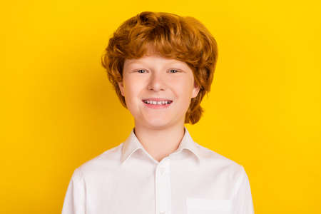 Portrait of young cute nice looking handsome boy first-grader wear school uniform isolated on yellow color backgroundの写真素材