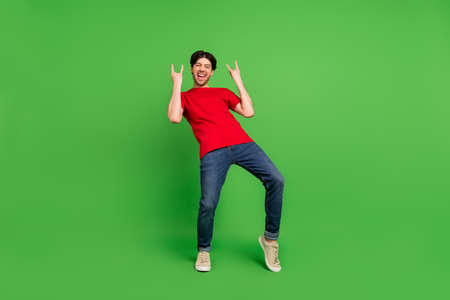 Photo of rocker funny fan guy enjoy concert show two horns gesture wear red t-shirt isolated green color backgroundの写真素材